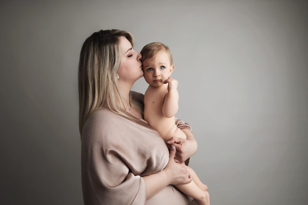 Mère blonde embrassant son bébé d'un an dans les bras, séance liens mère-enfant à Juziers par Rose Basile, photographe maternité Yvelines