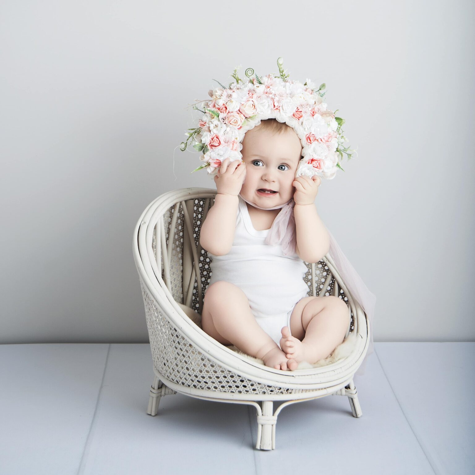 Bébé en body avec bonnet fleuri pour une séance extra-ordinaire.