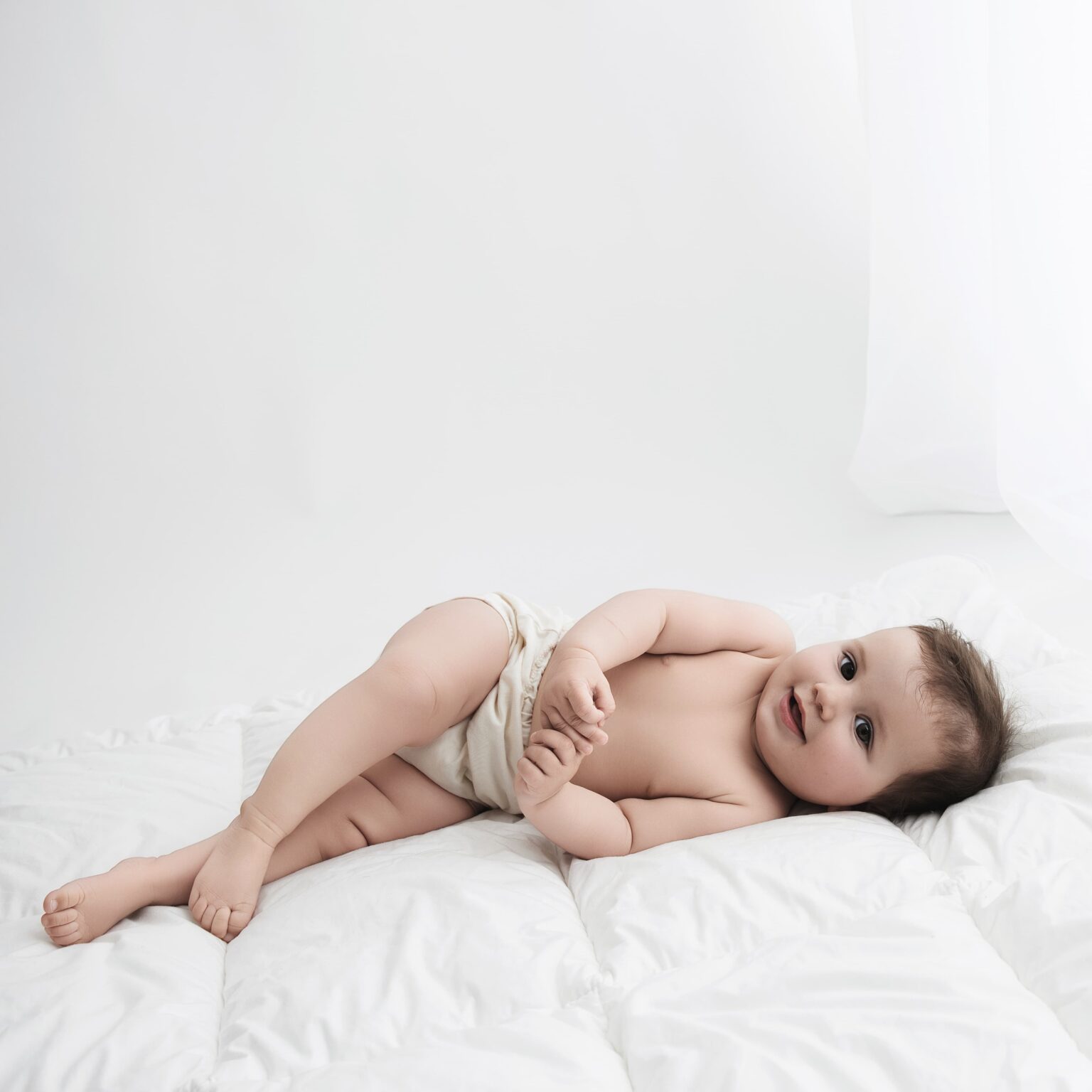 Bébé allongé sur une couette en culotte pour sa séance première année au studio.