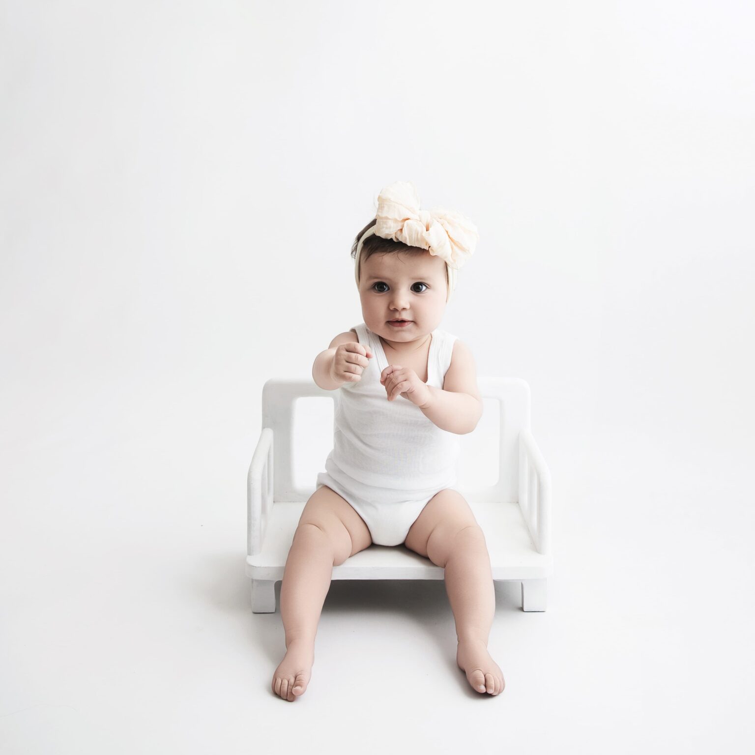 Petite fille de 12 mois en studio avec un body marcel du dressing qui joue à boxer.